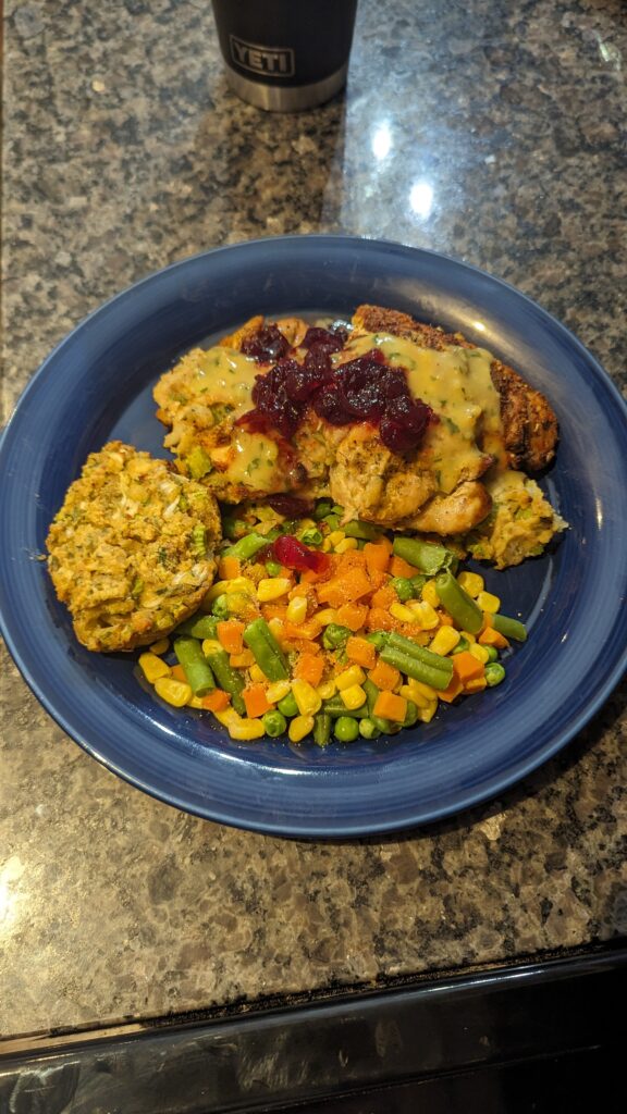 Cornbread Dressing stuffed chicken breast with chicken gravy, mixed vegetables, cranberry sauce, and extra cornbread dressing muffin